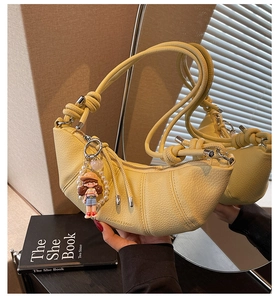 Detail of yellow croissant bag with lychee texture and pearl doll pendant charm