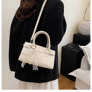 Détail du sac seau blanc cassé gaufré crocodile avec perles et nœud en dentelle
