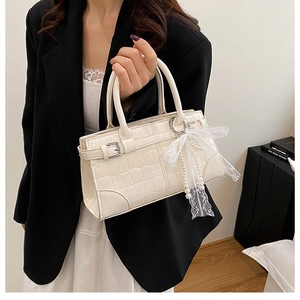 Détail du sac seau élégant en relief crocodile crème avec nœud en dentelle et pendentif perle