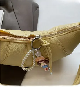 Close-up of yellow crescent bag with silver zipper and pearl charm decoration
