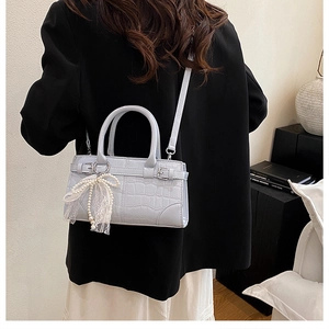 Détail du sac seau bleu clair à motif crocodile avec nœud en dentelle et perles