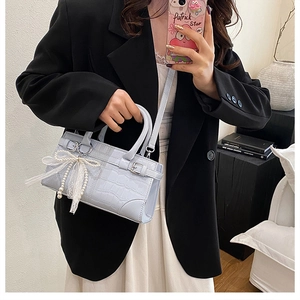 Détail du sac seau bleu clair à motif croco avec nœud en dentelle perle et anneaux argent