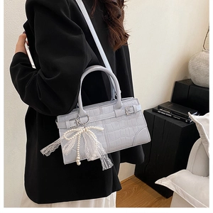 Détail d'un sac seau bleu clair gaufré crocodile avec un élégant nœud en dentelle
