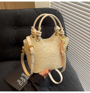 Detailed view of cream-colored bucket bag with embossed animal patterns and knot handles