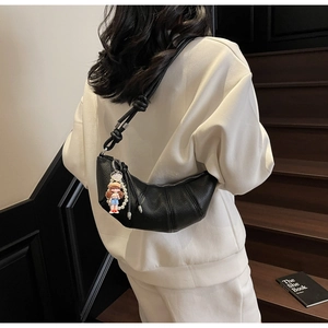 Detail shot of black lychee grain leather croissant bag with knotted strap on model