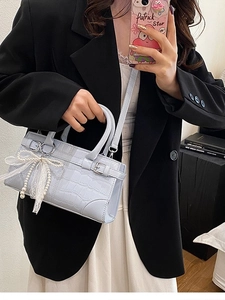 Sac seau bleu à motif crocodile avec nœud en dentelle perlée porté par un mannequin