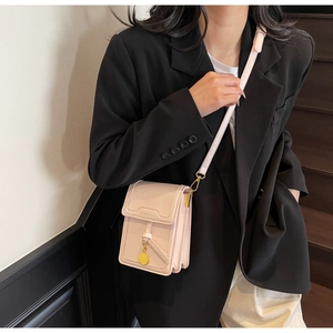 Close-up of a small light pink crossbody phone bag with gold charm and thin shoulder strap