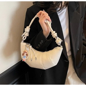 Close-up of cream crescent bag featuring lychee grain leather and knotted strap detail