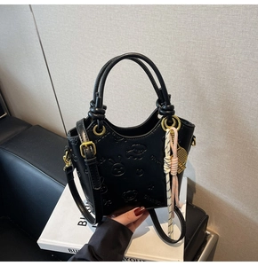 Detailed view of embossed cartoon animals on a black leather bucket bag with gold hardware