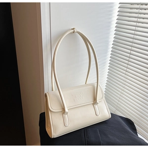 Detail view of cream white shoulder bag with embossed letters and sleek strap design