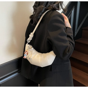 Detail of off-white lychee textured crescent bag with knotted strap and pearl charm