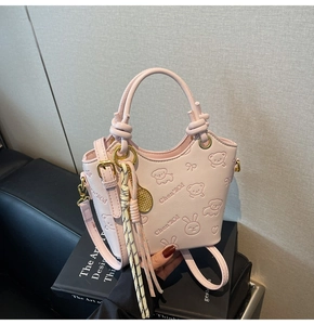 Detailed view of pink embossed bucket bag with animal patterns and knot handle