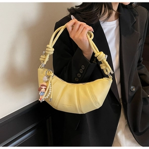 Close-up of yellow crescent shoulder bag with litchi leather texture and pearl chain detail