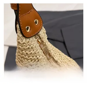 Detail of premium golden metal zipper and brown leather strap on handwoven straw beach bag