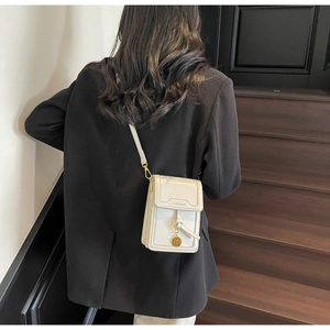 Detailed view of a white leather crossbody phone bag with gold charm and strap