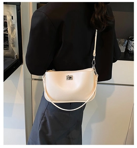 Detail view of cream-colored minimalist underarm bag with metallic rotating lock and long strap