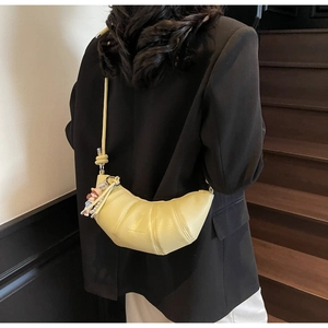 Detail of light yellow crescent bag showing lychee grain leather and pearl chain pendant