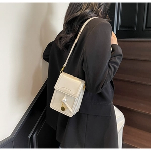 Detail of cream-colored crossbody phone bag with gold hardware and embossed lettering