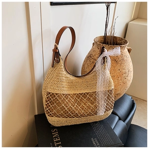 Detail of hand-woven straw shoulder bag with leather strap and white lace bow decoration
