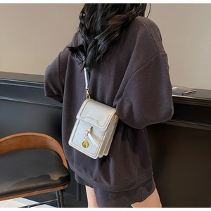 Silver-grey mobile phone crossbody bag with gold orb charm detail on a model