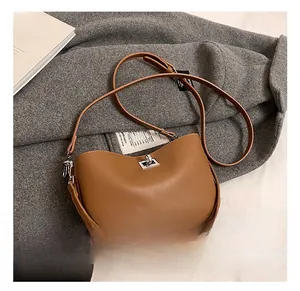 Close-up of brown matte leather shoulder bag with silver clasp on wool coat