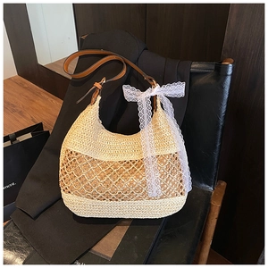 Close-up of woven straw tote bag with brown leather strap and white lace bow detail