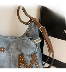 Close-up of denim tote bag with removable round pouch and leather strap detail