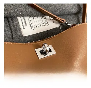 Close-up of silver metal twist lock on premium brown lychee pattern leather shoulder bag