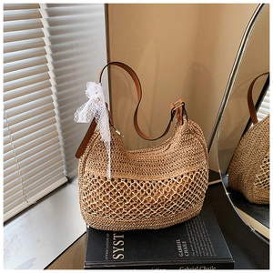 Detail of handwoven straw handbag with lace bow and leather strap on a minimalist setup