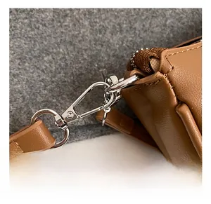 Close-up of silver metal hook and strap connection on a brown lychee pattern handbag