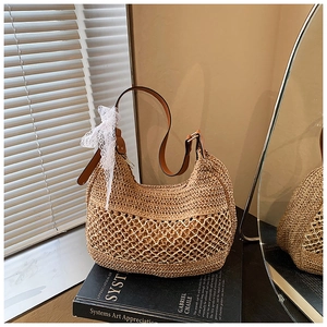 Detail of straw woven hobo bag with brown leather strap and white lace bow decoration