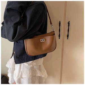 Detailed view of brown leather underarm bag featuring a classic metal twist lock closure