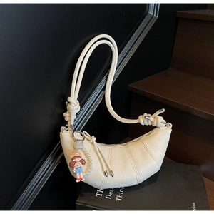 Detail of white lychee texture croissant bag with knot strap and cartoon charm