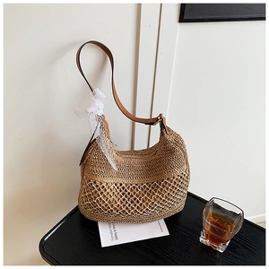 Detail of straw tote bag featuring intricate weave, mesh design and a white lace bow