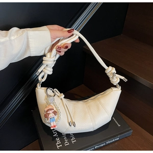 Detail of off-white dumpling bag featuring thick rope knot strap and pearl doll charm