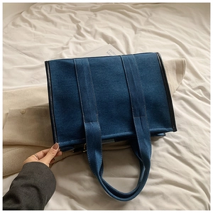 Vue détaillée du grand sac cabas en jean avec passepoil en cuir et larges poignées