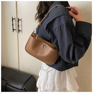 Detailed view of brown leather shoulder bag with silver metal buckle on a female model