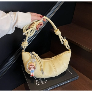 Detailed view of pale yellow croissant bag with lychee texture and thick rope knot strap