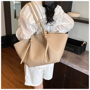 Detail of beige lychee pattern leather tote bag showing knotted shoulder strap and texture