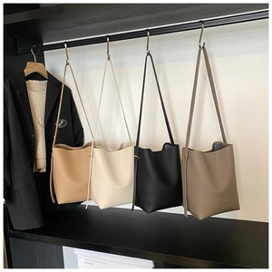Detailed row of minimalist leather bucket bags in khaki, beige, black, and dark brown