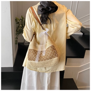 Close-up detail of woven straw tote bag with brown leather strap and white lace bow detail