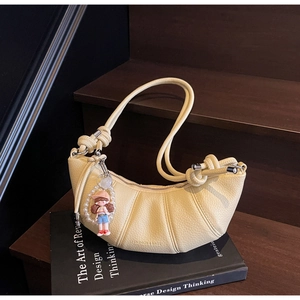 Detail of light yellow crescent bag with lychee texture and unique knot handle design