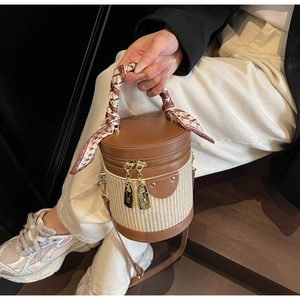 Close-up of a cylinder bucket bag with leather splicing and silk scarf handle detail