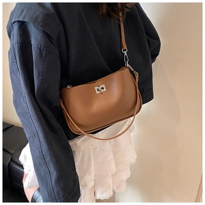 Detail of classic brown leather underarm bag with silver buckle worn by a model