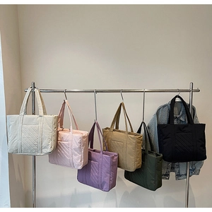 Detailed display of quilted puffer tote bags in six colors hanging on a metal rack