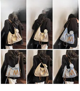 Detail view of large Hobo bag with M logo, rivets, and matching round coin purse detail