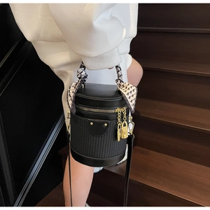 Detail of black cylindrical bag with woven texture and checkerboard silk scarf handle