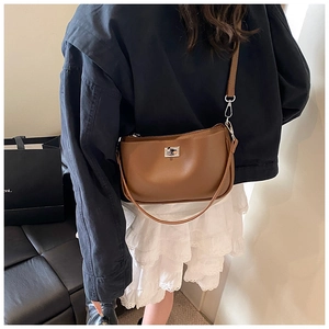 Detail view of a caramel leather hobo bag with silver buckle worn by a model