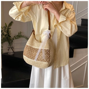 Detail of woven beige straw bag with brown grid patterns and elegant white lace ribbon