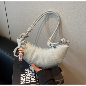 Detail of light blue crescent bag with pebble leather texture and pearl doll charm